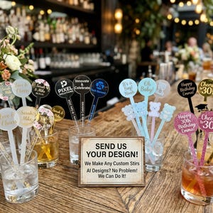 May include: A variety of custom drink stirrers with personalized text and designs, including wedding, birthday, and corporate event themes. The stirrers are in clear glasses with drinks, and a sign reads "SEND US YOUR DESIGN!"