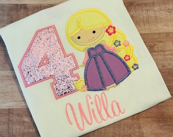 May include: A cream-colored t-shirt featuring a princess design with a number 4 in pink glitter and the name "Willa" in pink script. The princess has blonde hair and wears a purple dress.