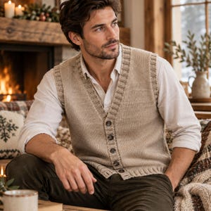 Peut inclure: Un gilet en tricot beige boutonné avec un col en V et des bordures côtelées, porté sur une chemise blanche à manches longues et col, associé à un pantalon vert olive foncé. Le gilet présente un point jersey classique et cinq boutons foncés.