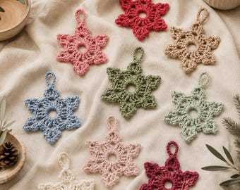 May include: A collection of nine crocheted snowflake ornaments in various colors including red, pink, blue, green, beige, and cream. Each snowflake features a central circular opening and a small loop at the top for hanging purposes.