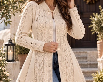 May include: A cream-colored cable knit cardigan featuring a V-neckline, long sleeves, and a button-down front closure. The garment has a flared silhouette with vertical cable knit patterns running down the front and sleeves.