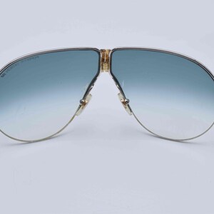May include: Vintage aviator sunglasses with a gold-tone metal frame and gradient blue lenses. The lenses transition from a darker blue at the top to a lighter blue at the bottom. The frame has a classic double bridge design.