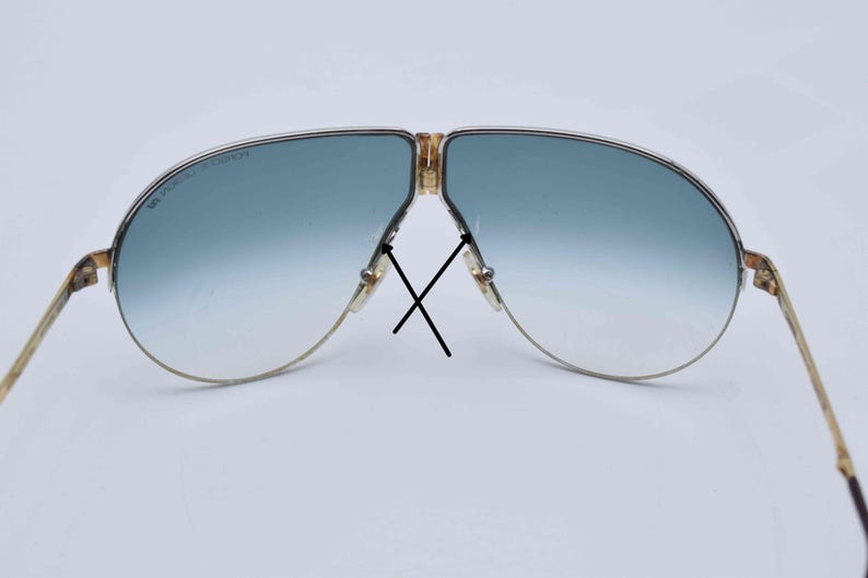 May include: Vintage aviator sunglasses with a gold-tone frame and gradient blue lenses. The lenses transition from a darker blue at the top to a lighter blue at the bottom. The frame has a classic design.