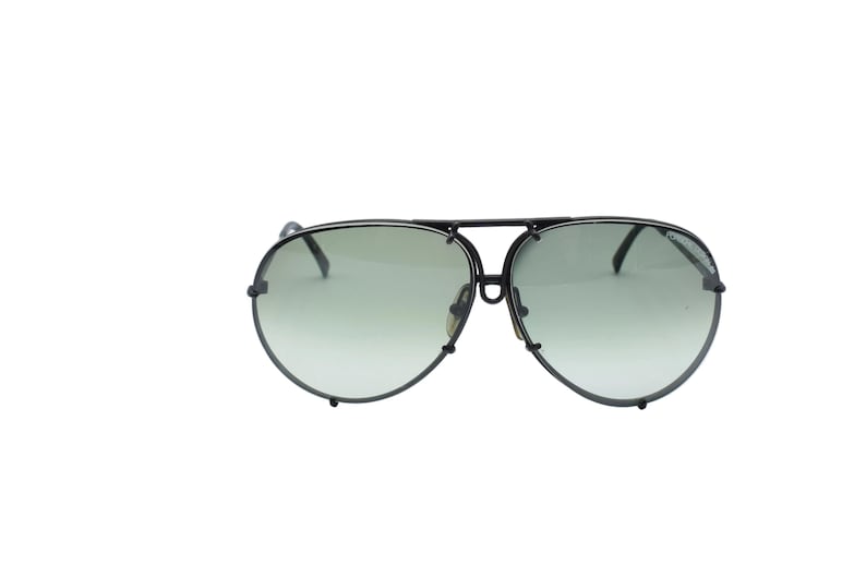K&ouml;nnte beinhalten: Aviator-Sonnenbrille mit schwarzem Metallrahmen und gr&uuml;n get&ouml;nten Gl&auml;sern. Die Sonnenbrille hat einen Doppelsteg und eine klassische Tropfenform. Ein modisches Accessoire zum Schutz der Augen.