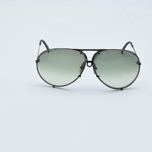 K&ouml;nnte beinhalten: Schwarze Aviator-Sonnenbrille mit Doppelsteg und Farbverlaufsgl&auml;sern. Die Gl&auml;ser gehen von einem dunkleren Farbton oben zu einem helleren Farbton unten &uuml;ber. Der Rahmen hat ein mattes Schwarz.