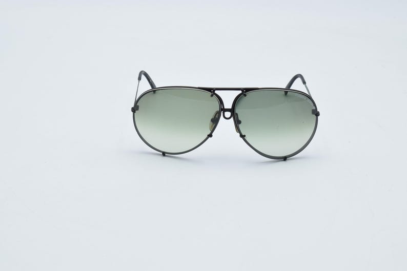 K&ouml;nnte beinhalten: Schwarze Aviator-Sonnenbrille mit Doppelsteg und Farbverlaufsgl&auml;sern. Die Gl&auml;ser gehen von einem dunkleren Farbton oben zu einem helleren Farbton unten &uuml;ber. Der Rahmen hat ein mattes Schwarz.