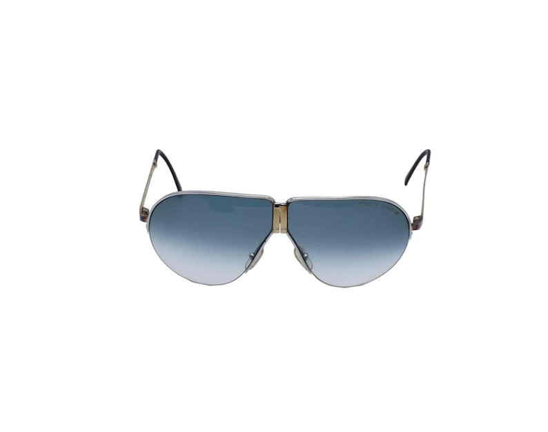 May include: Aviator-style sunglasses with a gold-tone metal frame and gradient blue lenses. The lenses transition from a darker blue at the top to a lighter shade at the bottom. The temples are thin and black.