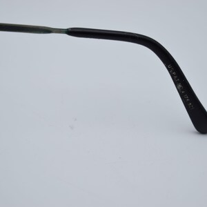 K&ouml;nnte beinhalten: Nahaufnahme des B&uuml;gels einer Brille. Der B&uuml;gel ist schwarz mit einem geschwungenen Design und einer abgerundeten Spitze. Der Text "DESIGN 02" ist auf dem B&uuml;gel sichtbar. Der Text "U.S. PAT. NO. 4,124,871" ist ebenfalls sichtbar.