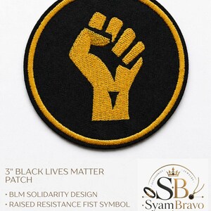 May include: A circular embroidered patch featuring a gold raised fist symbol on a black background with a gold border. The patch measures 3 inches in diameter and includes text stating 3" BLACK LIVES MATTER PATCH, BLM SOLIDARITY DESIGN, RAISED RESISTANCE FIST SYMBOL, EASY IRON-ON BACKING, and BLACK AND GOLD EMBROIDERY.