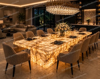 May include: A well-lit dining room with a large, illuminated marble dining table, seating twelve. The table is set with place settings, and the room is lit by a large chandelier and recessed lighting. Beige upholstered chairs surround the table.
