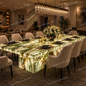 May include: A luxurious dining room featuring a large, illuminated onyx dining table with seating for twelve. The table is surrounded by cream-colored upholstered chairs. The room is lit by a chandelier and recessed lighting, creating a warm and inviting atmosphere.