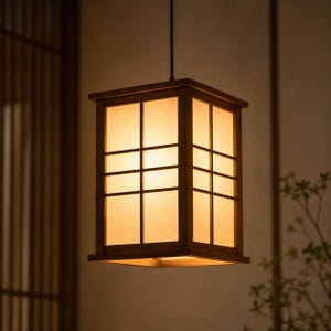Peut inclure: Un luminaire suspendu carré en bois avec un intérieur chaleureux et lumineux. La lumière présente un motif quadrillé sur le devant et les côtés, et est suspendue à un cordon noir. Le luminaire est de couleur marron chaud.