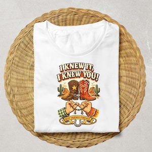 May include: A white t-shirt featuring a graphic print of two cowboy boots, one brown with a star and one red with a heart, above two hands performing a pinky promise. The text reads I KNEW IT, I KNEW YOU! and BEST FRIENDS FOREVER with a horseshoe.