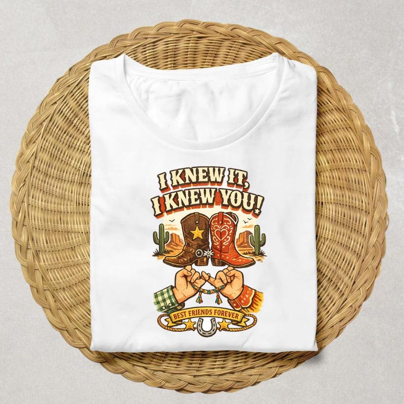 May include: A white t-shirt featuring a graphic print of two cowboy boots, one brown with a star and one red with a heart, above two hands performing a pinky promise. The text reads I KNEW IT, I KNEW YOU! and BEST FRIENDS FOREVER with a horseshoe.