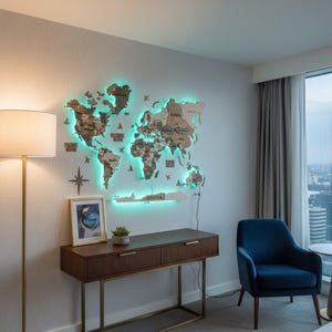 May include: A large, multi-layered wooden world map wall art piece featuring laser-cut continents and countries with integrated LED backlighting that emits a bright cyan glow. The map includes a decorative compass rose and text labels.