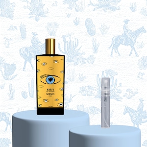 Könnte beinhalten: Ein rechteckiger Parfümflakon mit einem goldenen Etikett mit Augenmotiven und dem Text "MARFA EAU DE PARFUM MEMO PARIS". Daneben befindet sich ein kleiner, klarer Zerstäuber. Der Hintergrund ist ein hellblaues Muster mit Cowboy- und Wüstenmotiven.