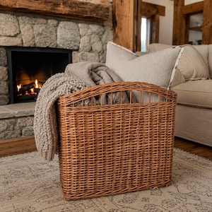 Peut inclure: Un panier rectangulaire en osier marron avec un motif tressé, contenant une couverture en tricot beige pliée et un coussin gris clair. Le panier présente un bord supérieur incurvé et est fabriqué en roseau naturel avec un tissage visible.