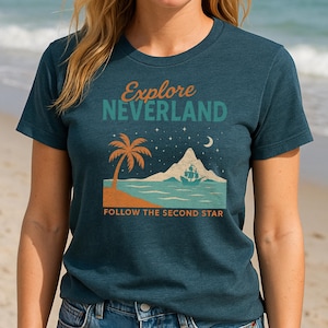 May include: A teal blue t-shirt with a graphic design of a palm tree, a mountain, a ship, and stars. The text "Explore Neverland" and "Follow the Second Star" are printed on the shirt.