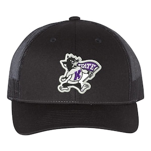 May include: Black and purple embroidered trucker hat with a cartoon cat mascot holding a flag that says "K-State".