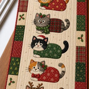 May include: A rectangular quilted table runner featuring five appliqued cats in festive holiday attire. The cats are arranged vertically on a cream background, surrounded by a border of red and green squares with snowflake and tree patterns.