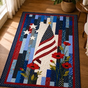 May include: A rectangular quilt featuring a central American flag design, white stars on a blue background, and red poppy flowers. The quilt is constructed from vertical strips of fabric in various shades of blue, red, and white with a dark border.