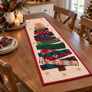 May include: A rectangular quilted table runner featuring a central Christmas tree design composed of various fabric strips in red, green, and white patterns. The runner has a cream-colored background with embroidered gold stars and a red border.