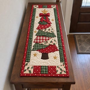 May include: A rectangular quilted table runner featuring a central Christmas tree applique made of layered fabric segments in red, green, and cream patterns. The tree is topped with a gold star and a red bow, surrounded by small gold stars.