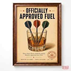 May include: A framed poster featuring the text OFFICIALLY APPROVED FUEL above a glass containing three darts with blue, red, and green flights. Below the glass, the text reads Three sharp objects, fueled by whisky. Ministry approved since 1952.