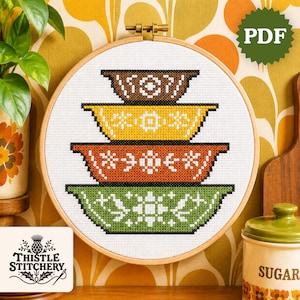 May include: A cross-stitch design in a wooden hoop depicts four retro bowls in brown, yellow, orange, and green, with floral and geometric patterns. The Thistle Stitchery logo is visible. The design is a PDF.