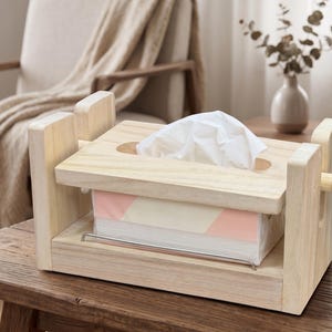 Könnte beinhalten: Ein Taschentuchbox-Halter aus hellem Holz mit mechanischem Pressdesign und seitlichem Drehknopf. Der Halter enthält eine rechteckige Box mit blassrosa und cremefarbenem geometrischem Muster, aus deren oberer ovaler Öffnung weiße Taschentücher ragen.