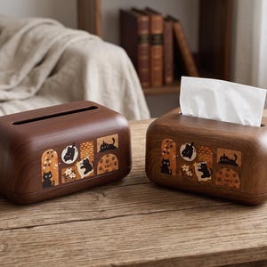 Könnte beinhalten: Zwei braune Holz-Taschentuchboxen. Jede Box hat eine dekorative Tafel mit schwarzen Katzenillustrationen auf beigem Hintergrund. Eine Box ist offen und enthält weiße Taschentücher.