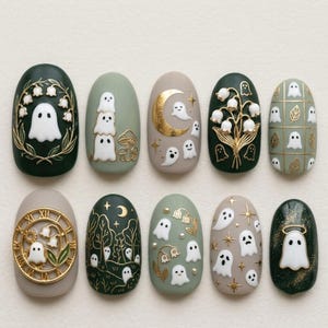 May include: A set of ten press-on nails featuring various designs including white ghosts, gold metallic moons, stars, and lily of the valley flowers. The color palette consists of dark forest green, sage green, and beige with gold accents.