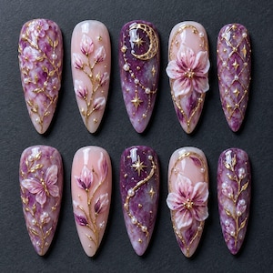 May include: A set of ten almond-shaped press-on nails featuring a purple and pink marble base. Designs include 3D gold floral branches, a gold crescent moon with stars, white pearls, and a butterfly motif, all accented with fine gold lines.
