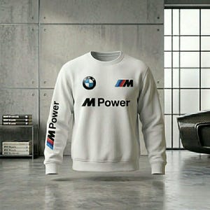 May include: A white sweatshirt with the BMW logo on the chest and the text "M Power" in black. The sleeve features the text "M Power" and the BMW logo. The sweatshirt has a crew neck and long sleeves.