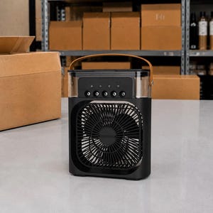 Puede incluir: Enfriador de aire port&aacute;til negro con una secci&oacute;n superior transparente y un asa marr&oacute;n. La parte delantera presenta un ventilador con un dise&ntilde;o circular. El enfriador se encuentra sobre una superficie blanca, con cajas de cart&oacute;n en el fondo.