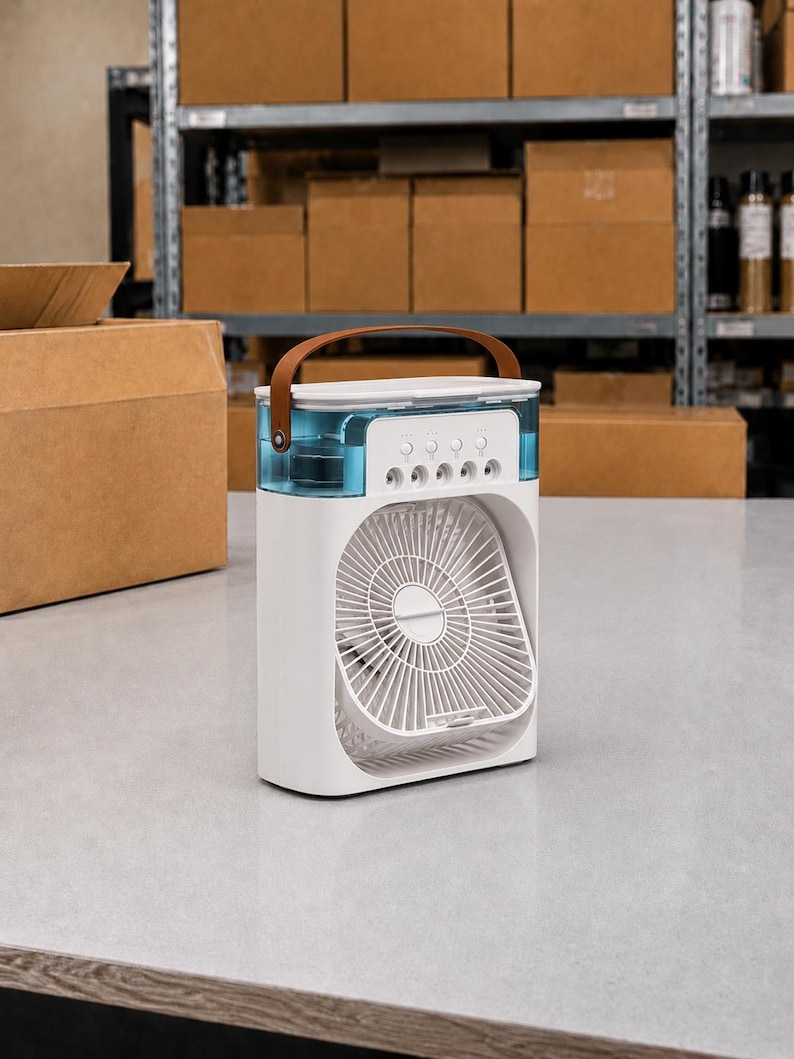 Puede incluir: Un enfriador de aire port&aacute;til blanco con un asa marr&oacute;n y un dep&oacute;sito de agua azul. El ventilador tiene una rejilla blanca y botones de control. La unidad est&aacute; sobre una superficie gris.