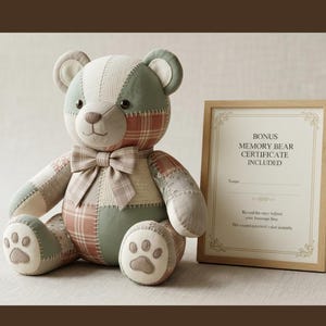 Könnte beinhalten: Ein Patchwork-Teddybär aus salbeigrünem und kariertem Stoff mit passender Fliege und Pfotenabdrücken an den Füßen. Daneben steht ein gerahmtes Zertifikat mit dem Text: BONUS MEMORY BEAR CERTIFICATE INCLUDED.