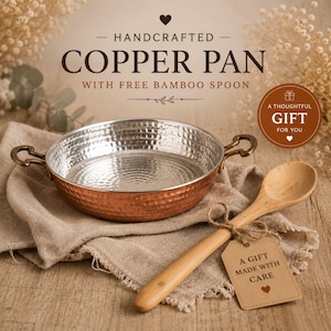 Puede incluir: Una sartén de cobre martillado con dos asas metálicas y un interior plateado, acompañada de una cuchara de madera clara. La imagen incluye el texto HANDCRAFTED COPPER PAN WITH FREE BAMBOO SPOON y A THOUGHTFUL GIFT FOR YOU.