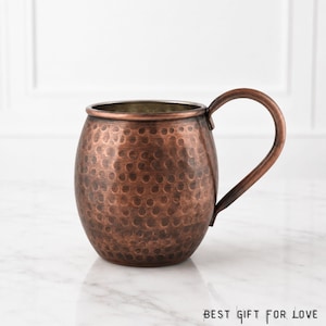May include: A copper Moscow Mule mug with a hammered finish and a large handle. The mug has a rounded body and a dark brown color. The text "BEST GIFT FOR LOVE" is at the bottom of the image.