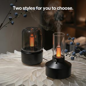May include: Two black aromatherapy diffusers with a warm orange glow are displayed. One has a rounded glass cover, the other a tall, cylindrical glass cover. The text "Two styles for you to choose" is at the top.