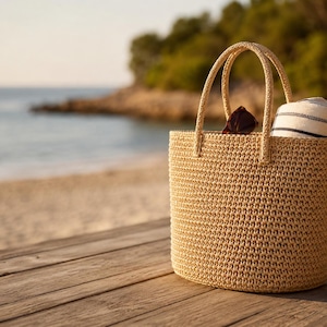 May include: A beige woven tote bag with two rounded handles. Inside the bag, a pair of dark brown sunglasses and a white rolled towel with thin black horizontal stripes are visible, protruding from the top opening of the structured bag.