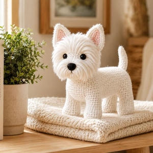 May include: A white West Highland White Terrier dog figurine crafted from crochet yarn. The dog has a textured, shaggy coat, pointed ears with pink inner details, black bead eyes, and a small black nose, standing in a classic alert pose.