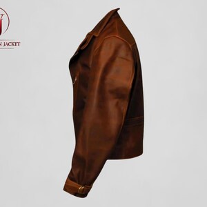 Pu&ograve; includere: Giacca in pelle marrone con collo e chiusura a zip. La giacca ha un design classico con polsino abbottonato e tasca. Il logo "WASHINGTON JACKET" &egrave; visibile nell'angolo in alto a sinistra.