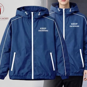 Pode incluir: Duas jaquetas com capuz azul marinho com detalhes brancos e o texto "KEEP SWIMMING". As jaquetas têm fecho de zíper e dois bolsos frontais. O logotipo da Washington Jacket está no canto superior esquerdo.