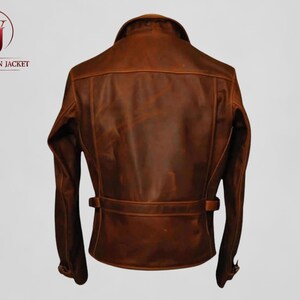 Pu&ograve; includere: Giacca in pelle marrone con colletto, maniche lunghe e dettaglio cintura in vita. La giacca ha un design classico ed &egrave; realizzata in pelle invecchiata. Il logo "Washington Jacket" &egrave; visibile nell'angolo in alto a sinistra.