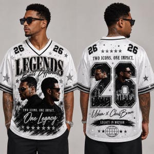 May include: A white V-neck jersey featuring black graphics of two men, the text "LEGENDS Built Different One Legacy" on the front, and "TWO ICONS. ONE IMPACT." with "Usher x Chris Brown" and the number "26" on the back, accented with stars.