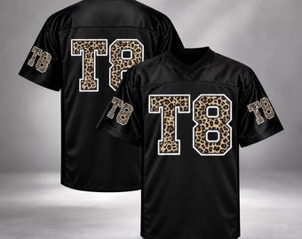 May include: A black short-sleeve jersey featuring the text T8 in a leopard print pattern with a white outline on the front and sleeves. The design is displayed on two jerseys, one showing the front and one showing the back view.
