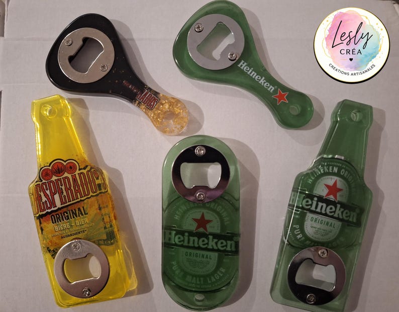 Pu&ograve; includere: Una collezione di apribottiglie di varie forme e colori. Ci sono due apribottiglie Heineken verdi, uno a forma di bottiglia. Sono presenti anche un apribottiglie Desperados giallo e un apribottiglie nero con manico dorato.