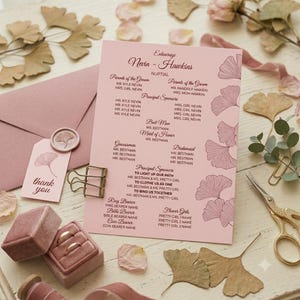 May include: A light pink wedding program card featuring dark pink ginkgo leaf illustrations and text listing the wedding party, including parents, sponsors, best man, maid of honor, groomsmen, bridesmaids, and flower girls, with a matching envelope and tag.