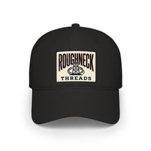 Könnte beinhalten: Schwarze Baseballkappe mit gebogenem Schirm. Auf der Kappe befindet sich ein rechteckiger Aufnäher mit dem Schriftzug "ROUGHNECK THREADS" in einer Vintage-Schriftart und einer Illustration eines Bohrgeräts. Der Aufnäher hat einen cremefarbenen Hintergrund.
